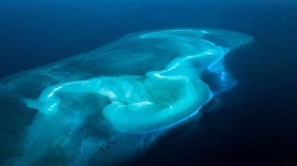 Fototapeta premium Glowing Submerged Sandbank Contrasts Beautifully with Surrounding Deep Blue Sea in Stunning Aerial Ocean View