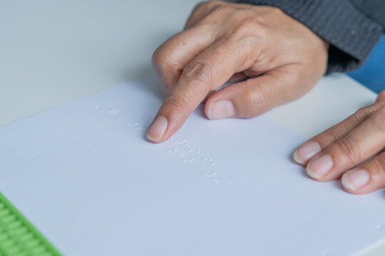 Blind people read Braille letters on white paper