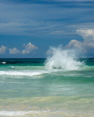 Fototapeta premium Powerful ocean wave crashing on tropical beach under dramatic clouds