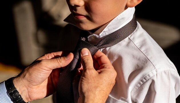 Father Tying Son's Tie: A close-up shot captures a father's hands gently adjusting his son's tie, symbolizing a tender moment of guidance and tradition.