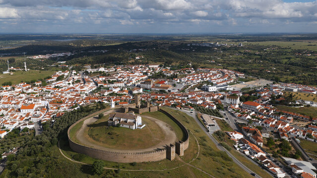 Aerial view of the historic Castle of Arraiolos, featuring its circular stone walls and central church, overlooking the white-washed town in Arraiolos, Evora District, Portugal.