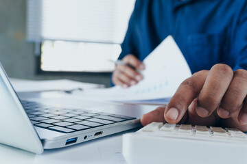 Fototapeta premium Business professional reviewing financial documents and calculating expenses on laptop with calculator at desk, personal finance management, accounting analysis and budget planning in modern workspace
