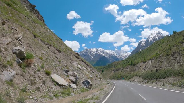 4K POV shot of a vehicle moving on a highway in front of snowy Himalayan mountain peaks during the summer season as seen near Keylong in Lahaul and Spiti district, Himachal Pradesh, India. 