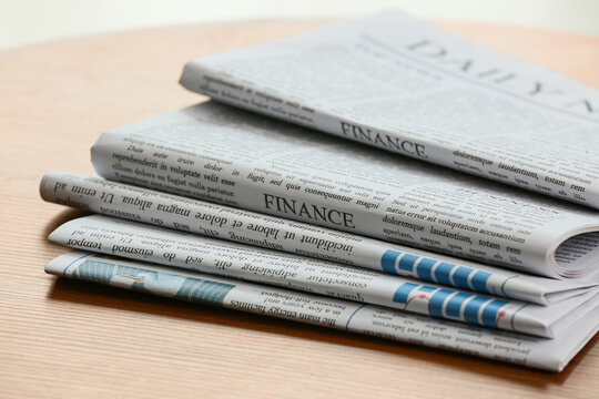 Stack of folded finance newspapers on wooden table