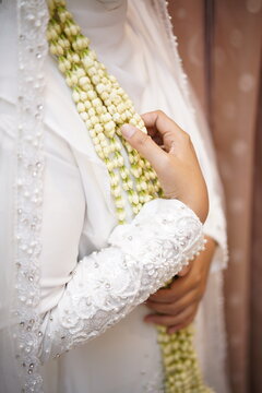 Bride holding traditional jasmine flower garland in white wedding dress
