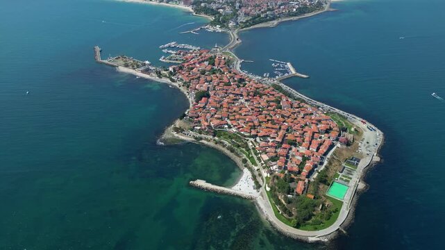 Slow right drone rotation reveals historic Nessebar peninsula surrounded by the Black Sea and traditional old town architecture in Bulgaria.