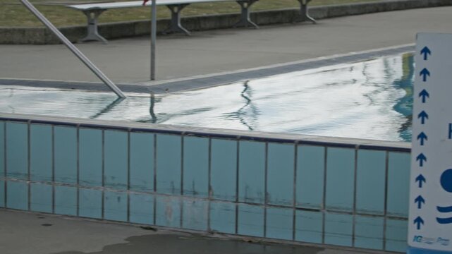 Pool lane signage indicating designated fast and slow swimming lanes beside an outdoor aquatic centre, promoting swimmer safety and lane etiquette. Panning shot.