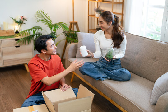 Happy young couple relocating in a new apartment. Young woman and man working and arranging the new property they just bought. Moving stuff and boxes together.