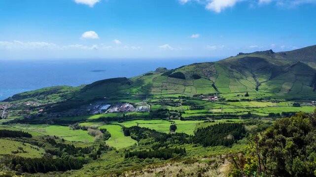 Scenic panoramic view showcasing patchwork fields rolling hills and the Atlantic Ocean from a mountain viewpoint on Flores Island Azores Portugal