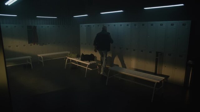Young Man in Blue Jeans and Vest Enters Modern Locker Room with Noticeable Limp, Opens Grey Locker With Key, and Starts Taking Out Personal Items From Sports Bag. Concept of Inclusion and Diversity.