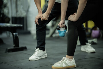 Fototapeta premium Young man and woman training together in gym, lifting dumbbells, building strength, fitness, wellness, confidence, teamwork, and healthy active lifestyle.