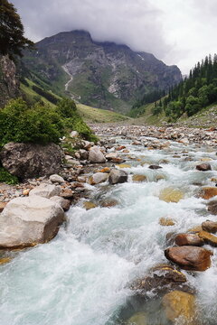 hampta river flowing through the lush green mountain valley, chika campsite area, hampta pass trek, kullu valley near manali, himachal pradesh, india