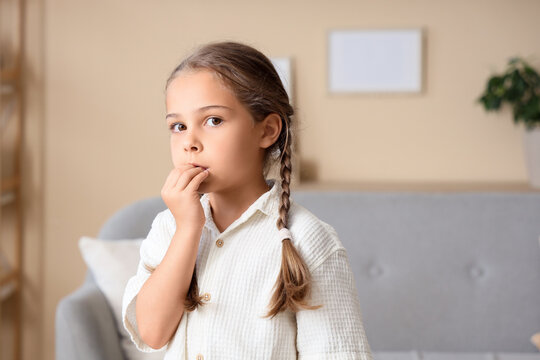 Little girl biting nails at home