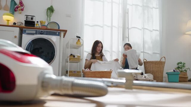 Mother and daughter fold clean laundry together at home, encouraging teamwork, responsibility, and family bonding through daily household routines.