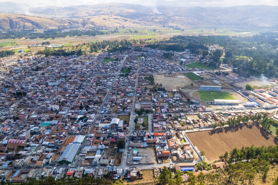 Aerial view of the town of Concepcion, featuring dense urban housing, a sports stadium, and surrounding agricultural fields in Concepcion, Junin, Peru.