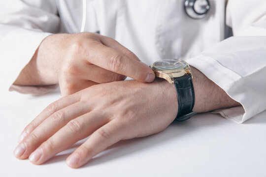 Close up of a male doctor checking his wristwatch. Healthcare and medical concept.