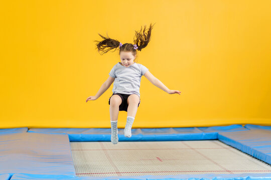 Happy little girl jumping on trampoline in fitness center