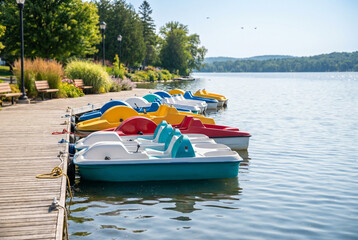 Fototapeta premium Colorful paddle boats docked along a wooden boardwalk by the lake 