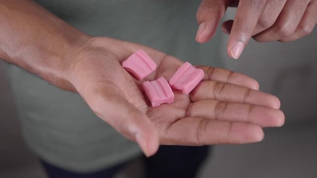 Hands show several pink chewing gum pieces,