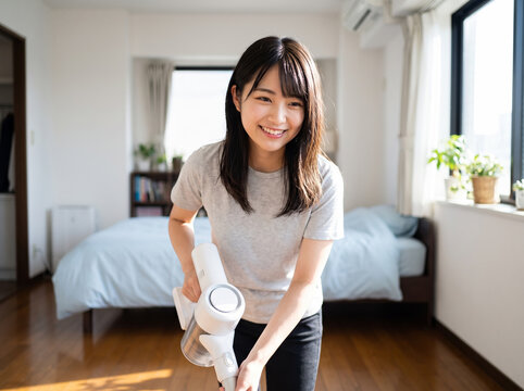 白いコードレス掃除機で床掃除をする女性
