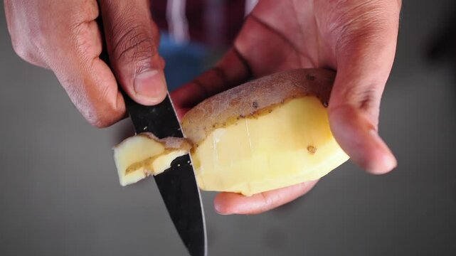 Peeling a potato with a knife in a kitchen