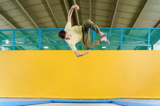 Teenage boy jumping on trampoline park in sport center 