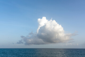Fototapeta premium One big white cloud in blue sky over sea landscape. Cloud above ocean water panorama, horizon, beautiful tropical caribbean summer day seascape panoramic view, cloudy weather with copy space