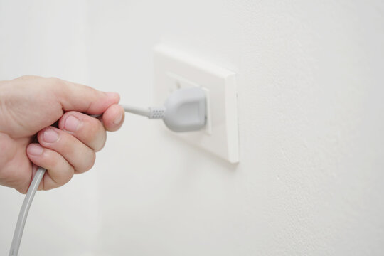 close up hand plugging adapter Electrical appliances with outlet socket plug  ,electric safety concept