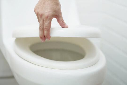 man hand opening the toilet lid.