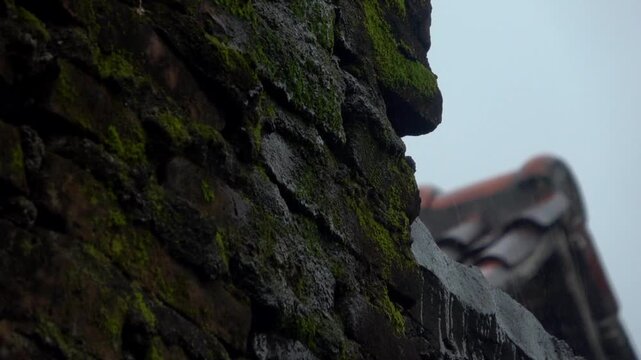 A slow motion shot of heavy stormwater rushing and gushing out from a broken, overflowing metal roof gutter drainage pipe during a torrential storm.
