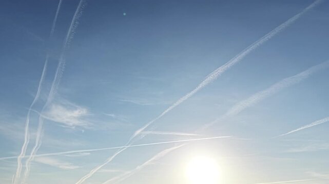 Jet trail patterns stretching through calm morning sky