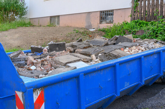 Blue construction skip container filled with concrete rubble and demolition waste