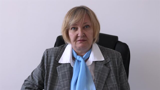 Senior businesswoman speaking and reacting during an online meeting or video call. Mature professional woman listening, surprised and concerned during remote communication.