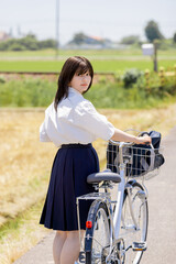 Obraz premium 自転車を押しながら振り返る女子高校生の通学風景