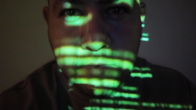 Computer hacker working in dark room with green programming code projected on his face, cyber security concept