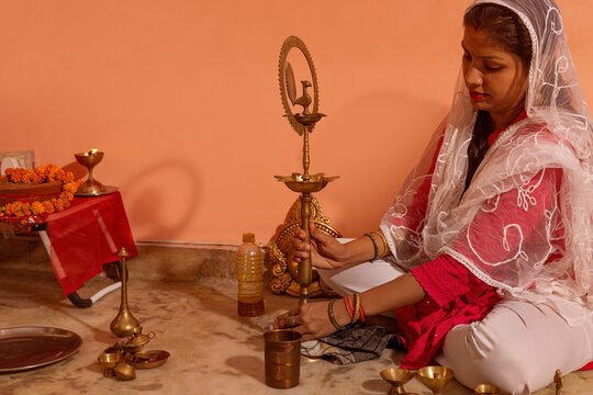 Woman arranging brass items for a religious ceremony.