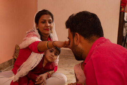 Woman applying tilak on a man's forehead during a ceremony.