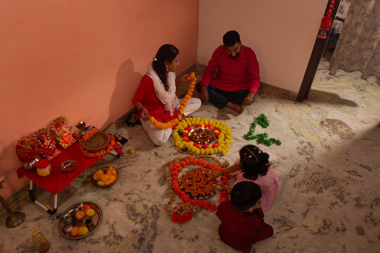 Family creating a colorful rangoli design for a festival.