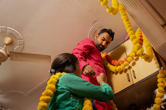 Couple decorating kitchen with festive garlands.