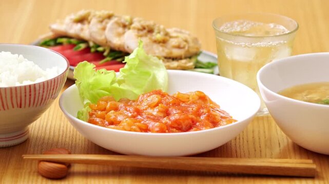 Shrimp with chili sauce (ebi chili) on a wooden dinner table, with bang bang chicken (banbanji) in the background, rack focus from blurry to sharp.