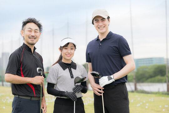 ゴルフレッスン場でゴルフのレッスンや習い事の、笑顔でゴルフを楽しむ男女のゴルファーイメージ　先生と生徒の3人のカメラ目線上半身