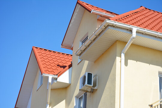 Roof gutter system on modern house with red tile roof, rain gutter, downspout and pitched roofing