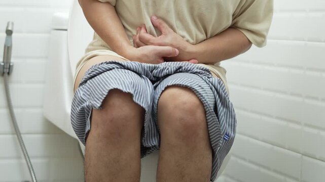 portrait of a man suffers from diarrhea his stomach painful. ache and problem. of toilet bowl. constipation in bathroom. Hygiene, health care concept.