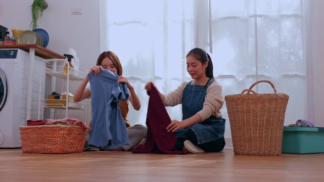 Woman laundry basket clothing home floor sorting chore domestic indoor scene with calm folding teamwork in bright tidy room near wicker basket window washer shelf casual comfort