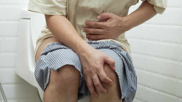 portrait of a man suffers from diarrhea his stomach painful. ache and problem. of toilet bowl. constipation in bathroom. Hygiene, health care concept.
