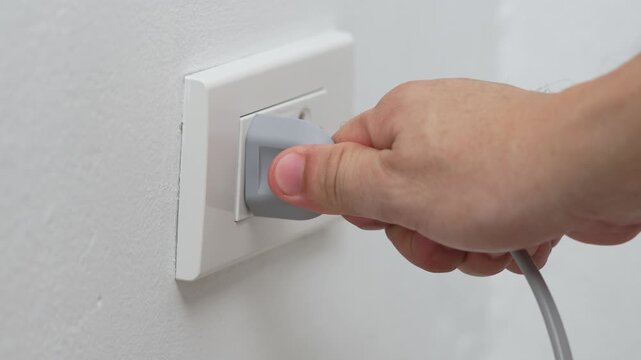 close up hand plugging adapter Electrical appliances with outlet socket plug ,electric safety concept