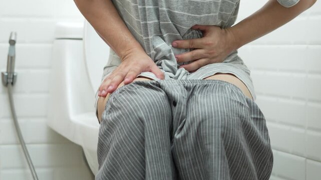 portrait of a man suffers from diarrhea his stomach painful. ache and problem. of toilet bowl. constipation in bathroom. Hygiene, health care concept.