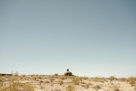 Two people celebrate on a rock in the desert