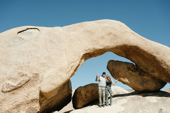Happy couple posing under a natural stone arch