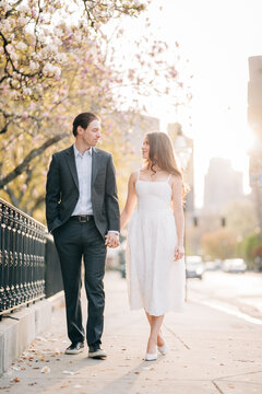 Couple walking holding hands on city street during spring sunset
